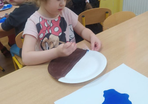 Lila maluje papierowy talerzyk