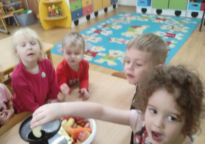 Dzieci wykonują sok marchewkowo- jabłkowy. Lila wkłada do wyciskarki jabłko.