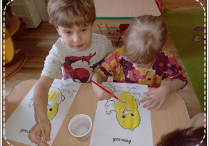 Antoś i Weronika starannie malują farbami swoje kurczaki