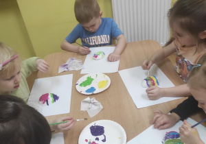 Dzieci malują gipsowe jajka.