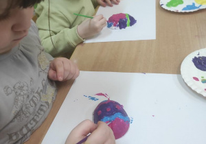 Dzieci malują gipsowe jajka.
