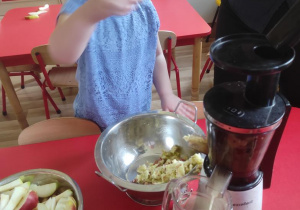 Dzieci pomagają przy robieniu soku jabłkowego.