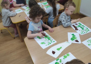 Dzieci malują drzewo a następnie stemplują palcami jego koronę.