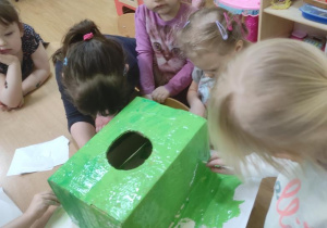 Dzieci malują podstawę drzewa na konkurs plastyczny.