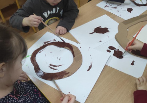 Dzieci malują koronę drzewa.