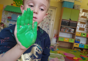 Sławek odciska rękę pomalowaną zieloną farbą, która później zostanie wykorzystana jako liść
