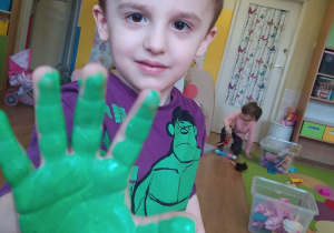 Marek odciska rękę pomalowaną zieloną farbą, która później zostanie wykorzystana jako liść