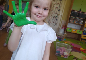 Lenka odciska rękę pomalowaną zieloną farbą, która później zostanie wykorzystana jako liść