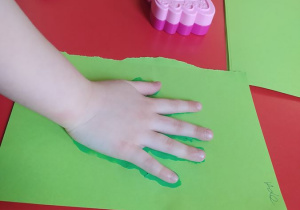 Aleks odciska rękę pomalowaną zieloną farbą, która później zostanie wykorzystana jako liść