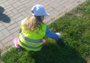 Hania Z. podnosi śmieci z trawnika.
