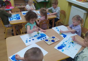Dzieci stemplują niebieskimi farbami
