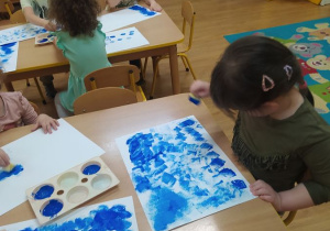Dzieci stemplują niebieskimi farbami