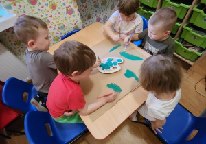 Dzieci malują na kolor zielony karton.