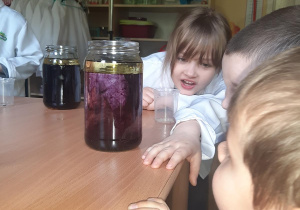 Lilka, Kuba i Adam obserwują przebieg eksperymentu w swoich słoikach z wodą.
