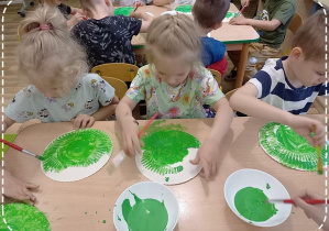 Laura, Hania K., i Jasio malują zieloną farbą talerzyki papierowe