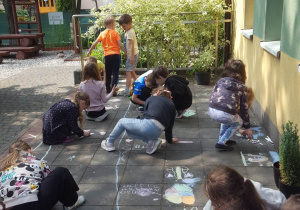 Dzieci ozdabiają swoimi rysunkami okolice przedszkola.
