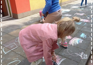 Dziewczynki rysują kredą po płycie chodnikowej
