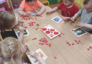 Dzieci przyklejają puzzle na ramkę.