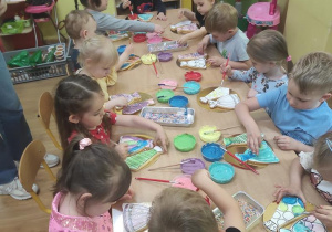 Dzieci dekorują lukrem ciastka w kształcie sukienki i krawata.
