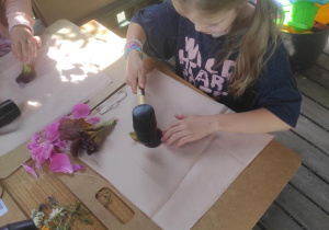 Dzieci układają na tkaninie kompozycje z kwiatów i wybijają gumowym młotkiem.