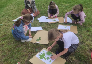 Dzieci układają kompozycję z liści.