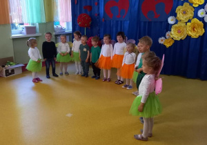 Dzieci stoją w półkolu i śpiewają piosenkę dla dzieci.