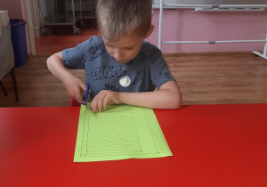 Adam przygotowuje kartkę kolorowego papieru na gąsienice.