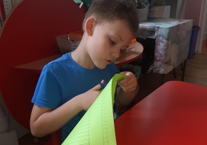 Szymon przygotowuje kartkę kolorowego papieru na gąsienice.