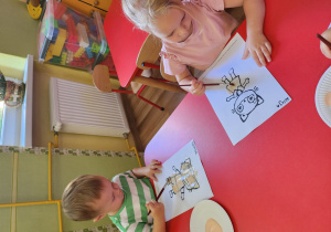 Oliwier i Alicja malują za pomocą farb obrazek Kici Koci.
