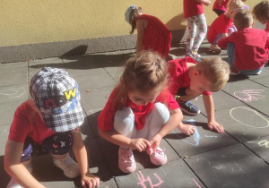 Dzieci rysują kredą na tarasie.