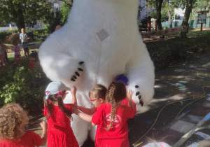 Dzieci przytulają się do białego niedźwiadka.