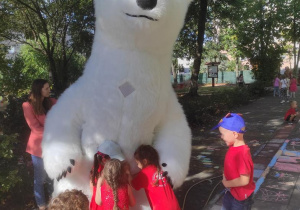 Dzieci przytulają się do białego niedźwiadka.