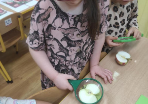 Zabawa badawcza- dzieci oglądają jabłko za pomocą lupy.