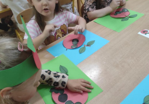 Dzieci składają z gotowych elementów jabłko z robaczkiem.