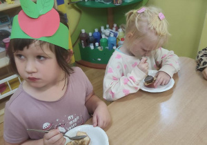 Dzieci zjadają pieczone jabłka z miodem.