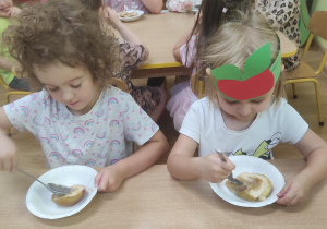 Dzieci zjadają pieczone jabłka z miodem.