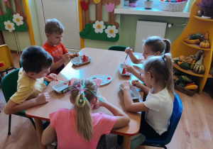 Dzieci malują farbami kolorowe kapelusze grzybków