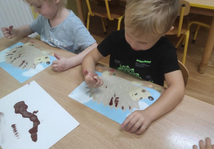Dzieci malują palcami jeże.