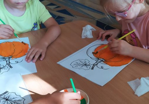 Dzieci malują sylwetę dyni farbami