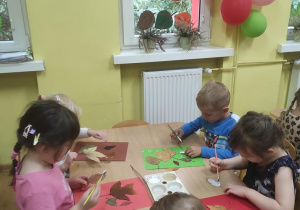 Dzieci tworzą obrazy z liści.