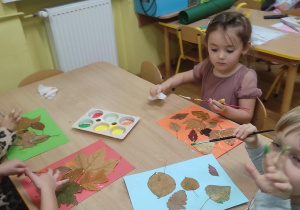 Dzieci tworzą obrazy z liści.