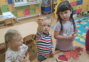 Dzieci liczą liście i pokazują taką samą liczbę kredek.