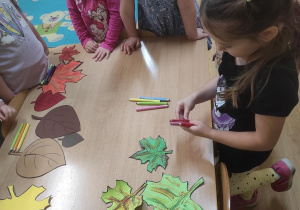 Dzieci liczą liście i odliczają taką samą liczbę kredek.