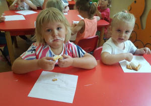 Dzieci jedzą gofry z bitą śmietaną.