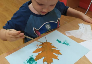 Oluś maluje farbami liście