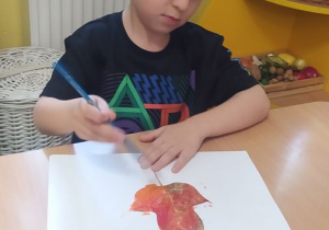 Michałek maluje farbami liście