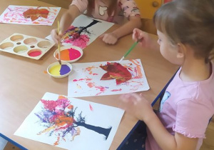 Dzieci malują farbami liście i stemplują nimi sylwetę drzewa