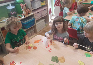 Agatka ,Helenka i Hania malują liście farbami.