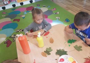 Julia i Oliwier malują liście farbami.