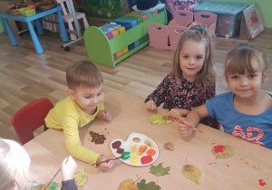 Zosia, Hania i Ignacy maluje liście farbami.